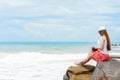 One pretty european woman is sittin on a stone close to shore of tropical sea and writing some idea, letter or job by Royalty Free Stock Photo