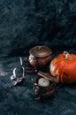 One pumpkin squash and copper or brass witch pots with candles black textured background Royalty Free Stock Photo