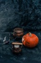 One pumpkin squash and copper or brass witch pots with candles black textured background Royalty Free Stock Photo