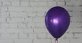One purple balloon on bricky white wall background