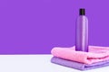 One purple cosmetic bottle on two towels on a lilac background. Spa concept Royalty Free Stock Photo