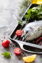 One raw dorado fish with spices, lemon and parsley in a black grill pan on a white concrete background. Healthy eating and tasty Royalty Free Stock Photo