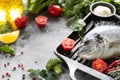 One raw dorado fish with spices, lemon and parsley in a black grill pan on a white concrete background. Healthy eating and tasty Royalty Free Stock Photo