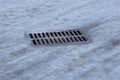 One rectangular gutter from an iron brown grate on a road in gray ice Royalty Free Stock Photo