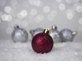 One red ball on the Christmas tree and four silver ones at the back, against a bokeh background Royalty Free Stock Photo