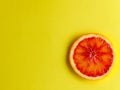 one red blood orange slice close up on yellow background.