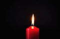One red candle burns on a dark background. Memory, memorial, romance, prayer, religion. Copyspace, free space, place for