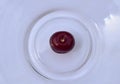 One red cherry in the center of the plate Royalty Free Stock Photo
