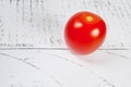 one red cherry tomato on a light wooden background. close up. vegetarian food Royalty Free Stock Photo