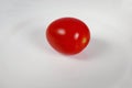 one red cherry tomato on a white plate.close up. Royalty Free Stock Photo