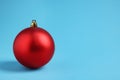 One red Christmas ball on light blue background. Space for text Royalty Free Stock Photo