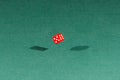 One red dice falling on a green table