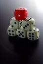 One Red game dice on top of stacked five white game dice Royalty Free Stock Photo