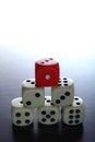 One Red game dice on top of stacked five white game dice Royalty Free Stock Photo