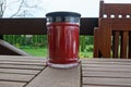 One red glass jar with a decorative candle stands on a brown board on the veranda