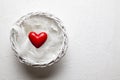 One red heart and feathers in white basket on plastered background Royalty Free Stock Photo