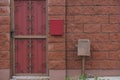 One red metal door with a wrought iron pattern and part of a brown fence wall Royalty Free Stock Photo