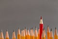 One red pencil sticking out of similars crowd on gray background Royalty Free Stock Photo