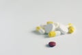 One red pill with many white and yellow  pills on white background. copy space Royalty Free Stock Photo