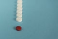 one red pill with many white and yellow pills on blue background. c Royalty Free Stock Photo