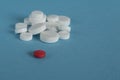 One red pill with many white and yellow  pills on blue background. copy space Royalty Free Stock Photo