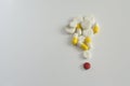 One red pill with many white and yellow  pills on white background. copy space Royalty Free Stock Photo