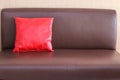 One red pillow on the brown leather sofa Royalty Free Stock Photo