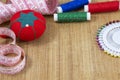 One red pincushion, tape and colourful threads with needle