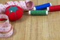 One red pincushion, tape and several threads with needle