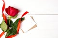 One red rose with red ribbon and mockup for greeting card on the white wooden background. Women`s day, mother day, valentines day