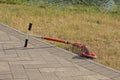 One red scooter lies in brown dry grass and gray sidewalk Royalty Free Stock Photo