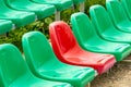 One red seat among different color green seats in a stadium