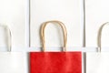 One red shopping bag in background of white bags isolated on white background. Royalty Free Stock Photo