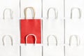 One red shopping bag in background of white bags isolated on white background. Royalty Free Stock Photo