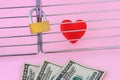 One red silk heart is in a cage locked with padlock. Few dollar banknotes are in front of this cage. To buy love or never sell Royalty Free Stock Photo