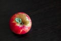 One red yellow ripe whole apple with green small leaf stands on a wooden dark brown table. Top view. Royalty Free Stock Photo