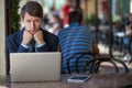 One relaxed young handsome professional businessman working with his laptop, phone and tablet in a noisy cafe.