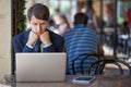 One relaxed young handsome professional businessman working with his laptop, phone and tablet in a noisy cafe.