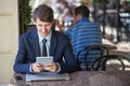 One relaxed young handsome professional businessman working with his laptop, phone and tablet in a noisy cafe.