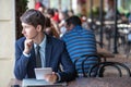 One relaxed young handsome professional businessman working with his laptop, phone and tablet in a noisy cafe.