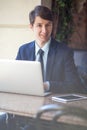 One relaxed young handsome professional businessman working with his laptop, phone and tablet in a noisy cafe.