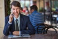 One relaxed young handsome professional businessman working with his laptop, phone and tablet in a noisy cafe.