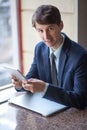 One relaxed young handsome professional businessman working with his laptop, phone and tablet in a noisy cafe.