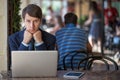 One relaxed young handsome professional businessman working with his laptop, phone and tablet in a noisy cafe.