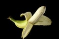 One ripe banana, half peeled, on a black background, isolated Royalty Free Stock Photo