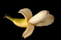 One ripe banana, half peeled, on a black background, isolated Royalty Free Stock Photo