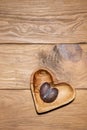 Ripe malformed plum on heart shaped plate on wooden table Royalty Free Stock Photo