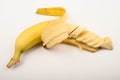 One ripe yellow partially peeled and cut into several parts banana on a white background. Close up Royalty Free Stock Photo