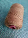 One roll of sewing threaded is brown against the background of the net