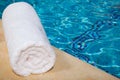 One rolled-up white towel by blue pool